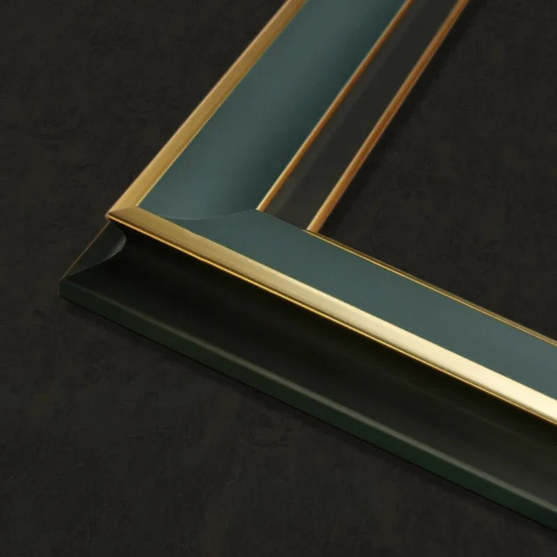 Close-up of a picture frame corner with a dark teal-green background and a polished gold inner border, set against a dark textured backdrop.